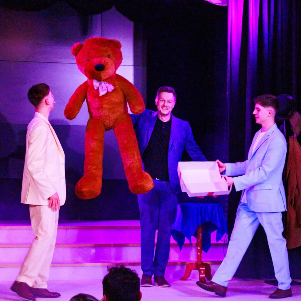 Ein großer Teddybär erscheint während einer Zaubershow auf der Bühne beim Drillingseffekt