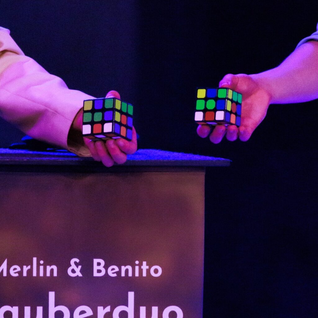 Zwei Rubik’s Cubes werden bei einer Zaubershow des Drillingseffekts in den Händen gehalten